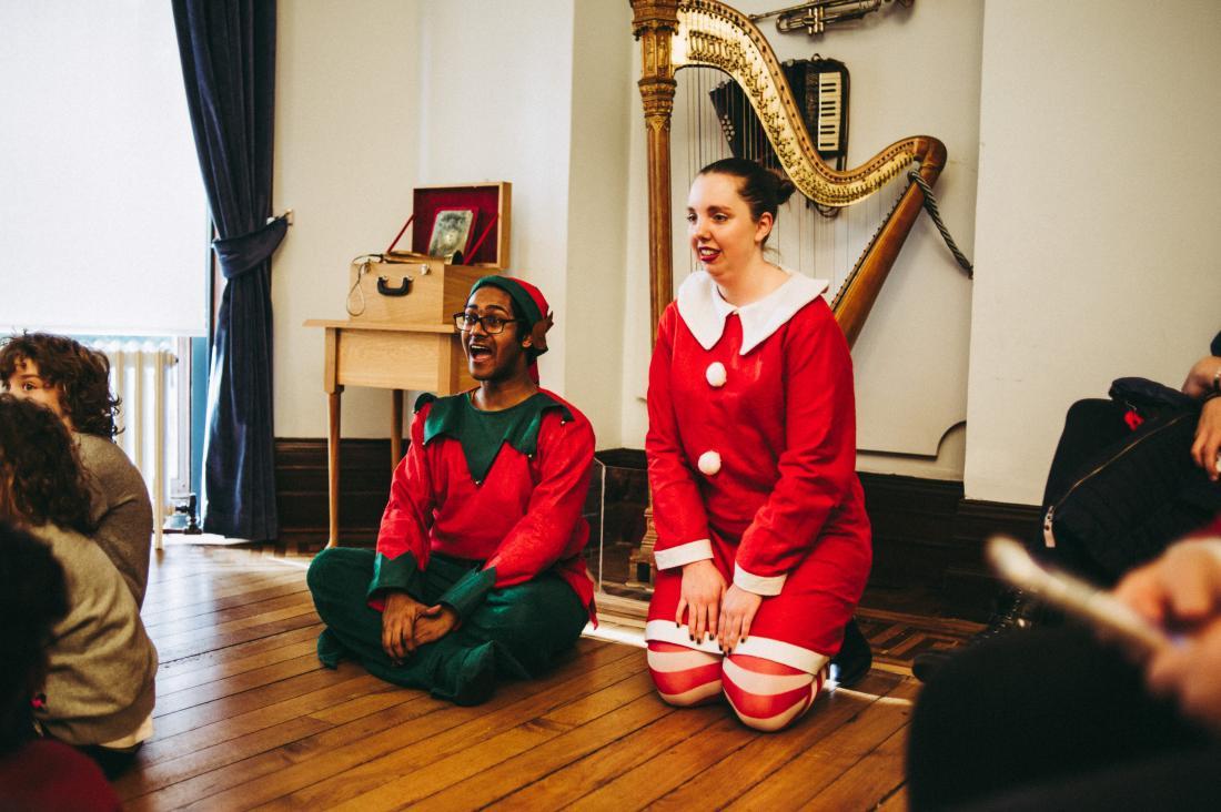 The Christmas Elves sit listening to a story by Father Christmas